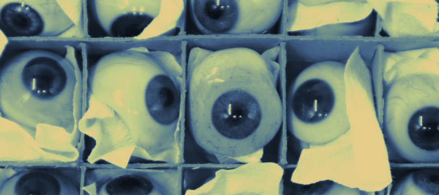 Close-up of eye prostheses in a cardboard box, each prosthesis individually wrapped in paper.
