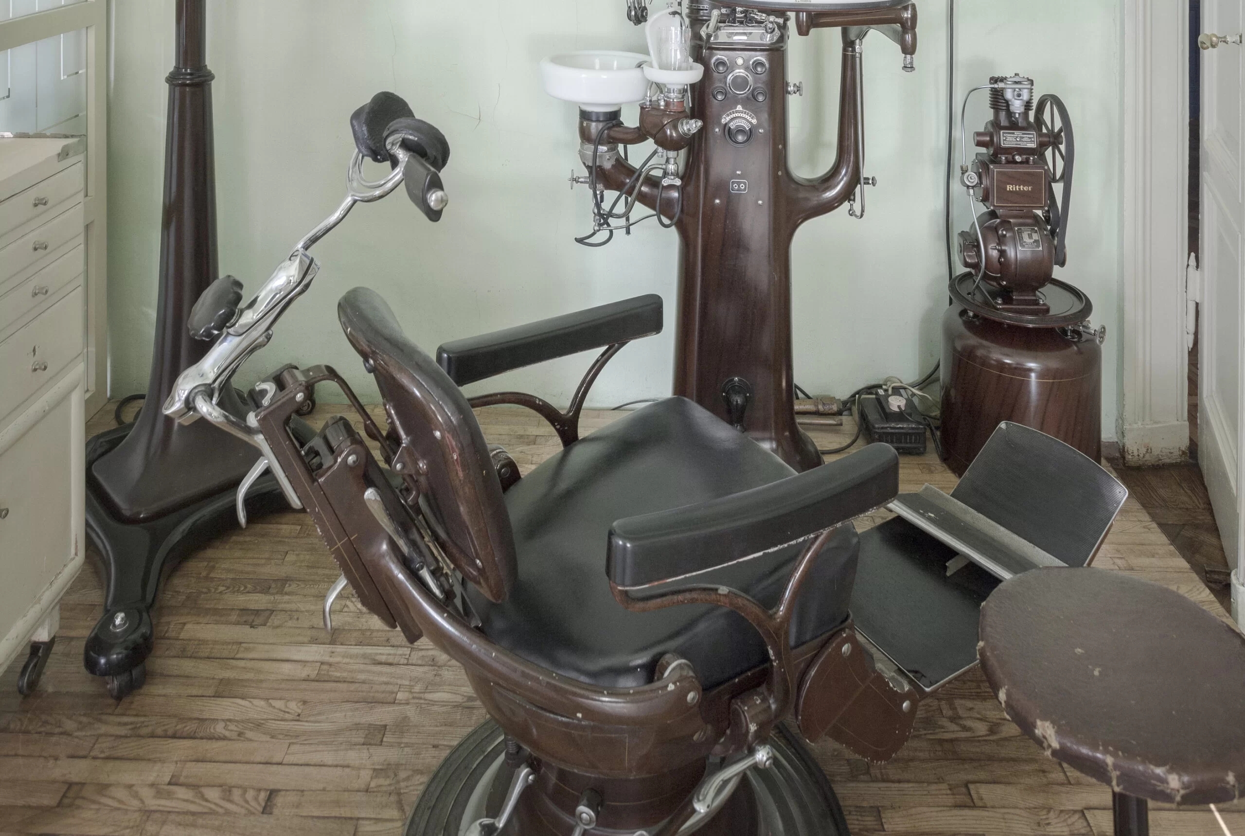 A dental chair surrounded by other brown wooden dental appliances.