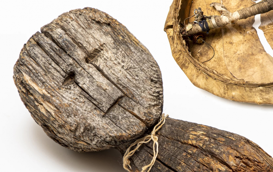 A shaman's wooden doll on a white background with a string around its neck
